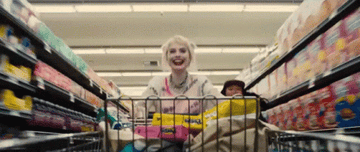 Harley Quinn running down supermarket aisle with shopping cart