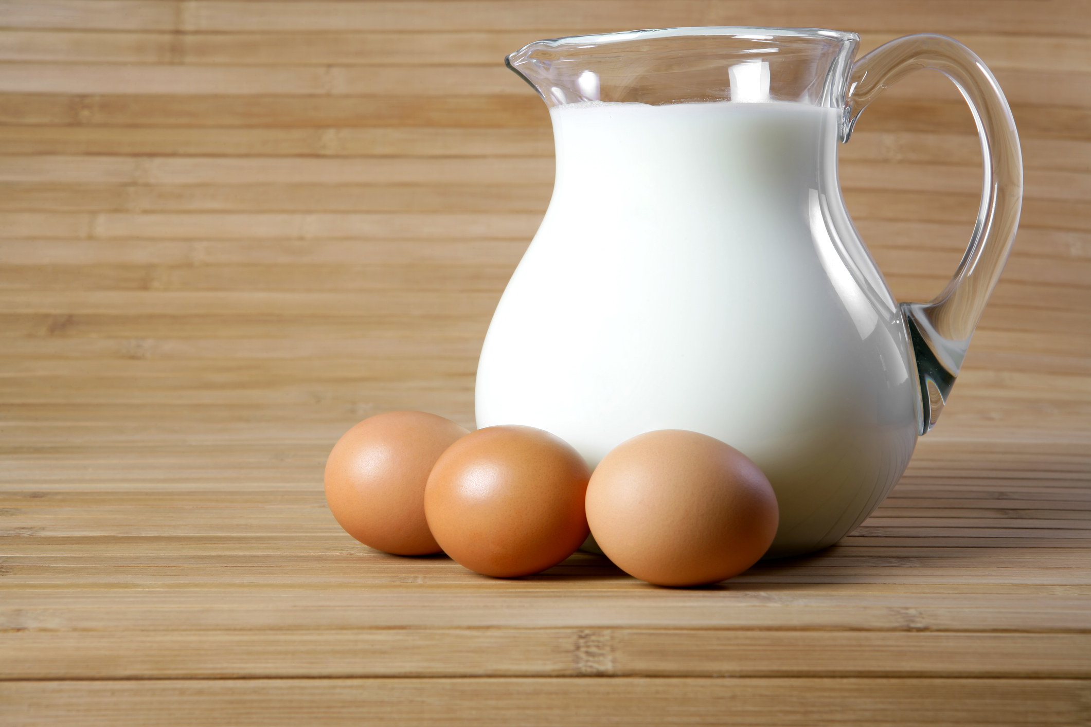 three eggs next to a pitcher of milk