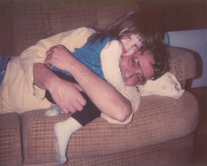 an old photo of a dad and young daughter hugging on the couch