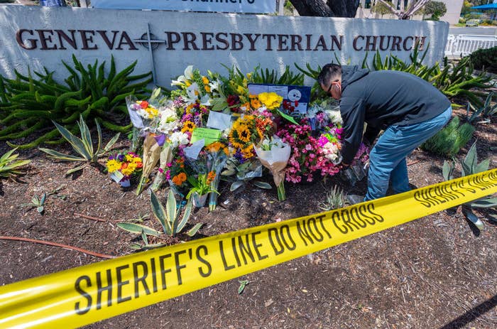 A person laying a bouquet of flowers in front of the church sign in an area cordoned off by police tape