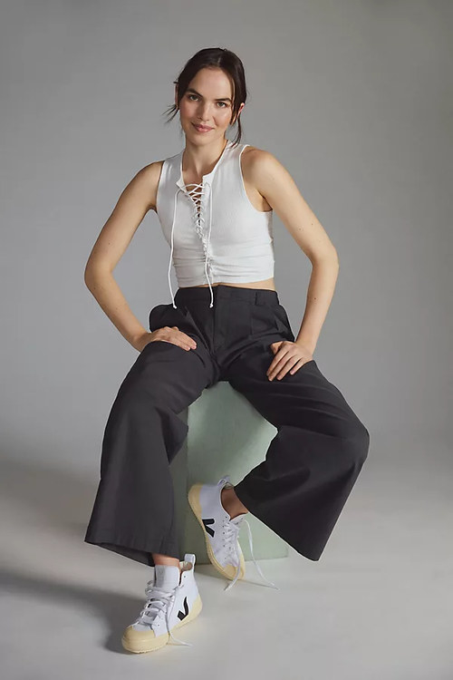 Model wearing white tie tank with black pants and white sneakers