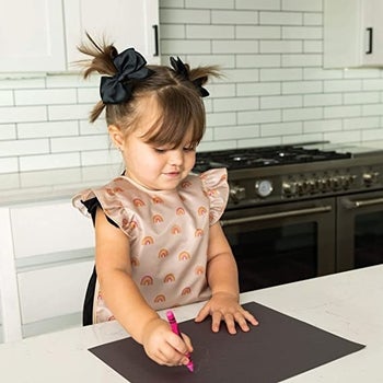 A child wearing the apron bib and coloring