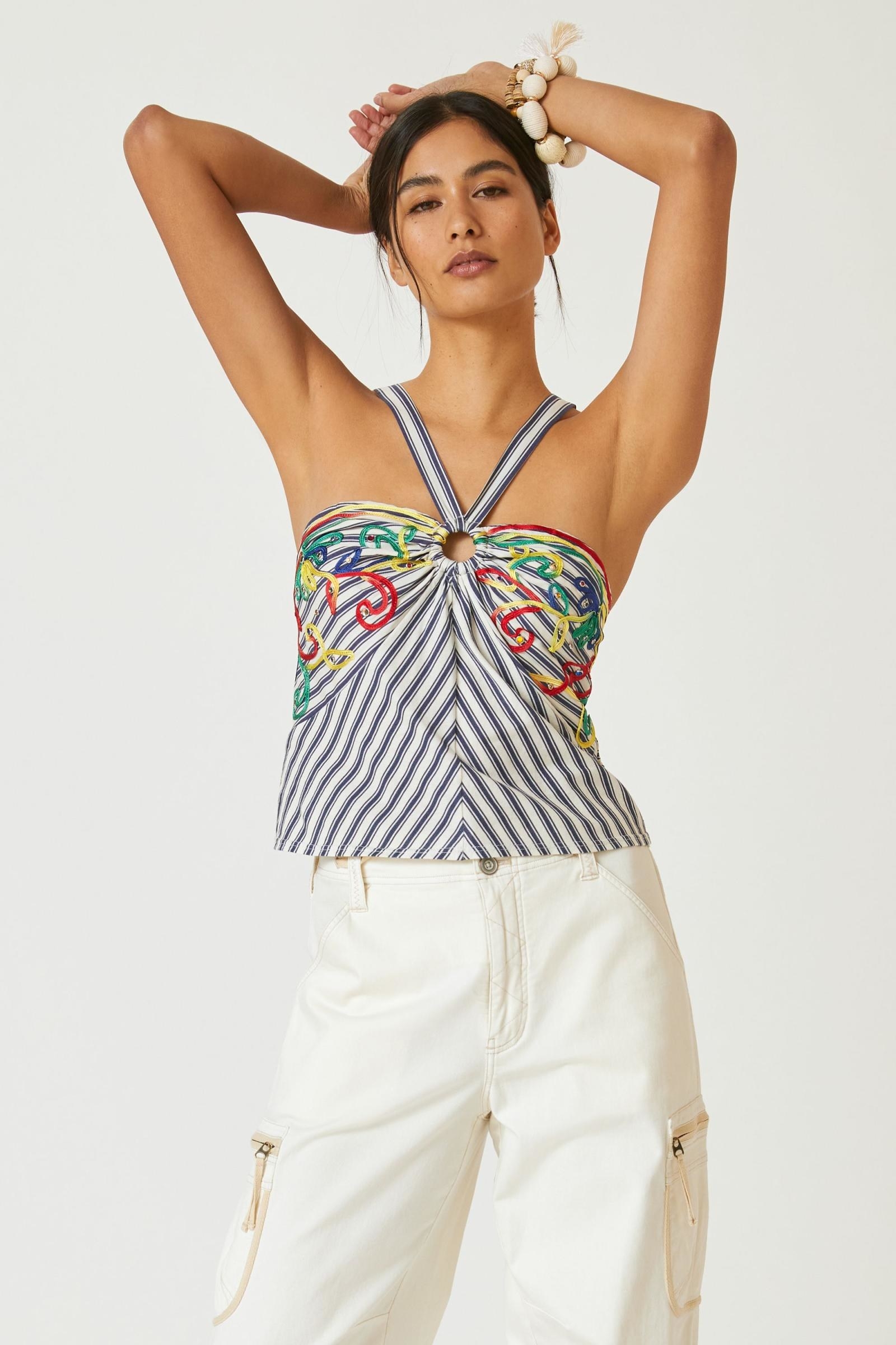 Model wearing navy blue and white striped halter top with green, red, yellow and blue embroidery on top