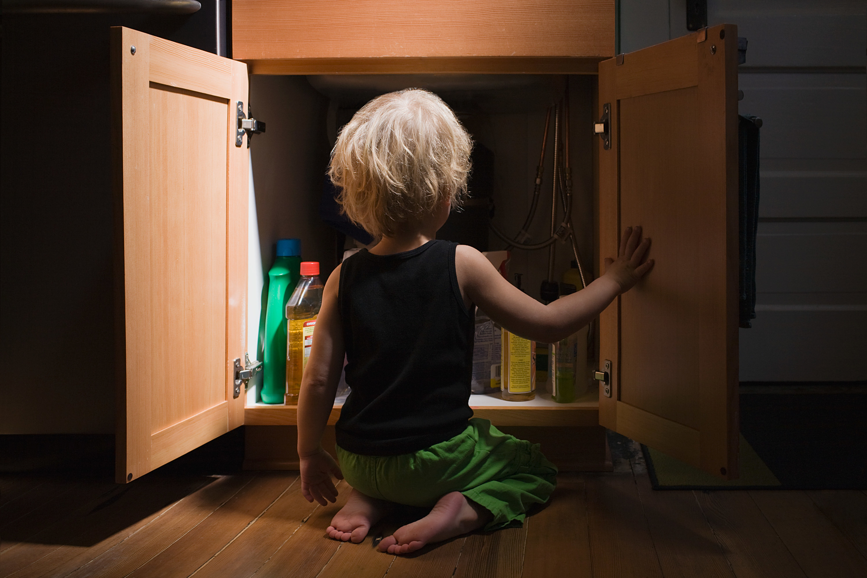 child looking in cabinet with cleaning supplies