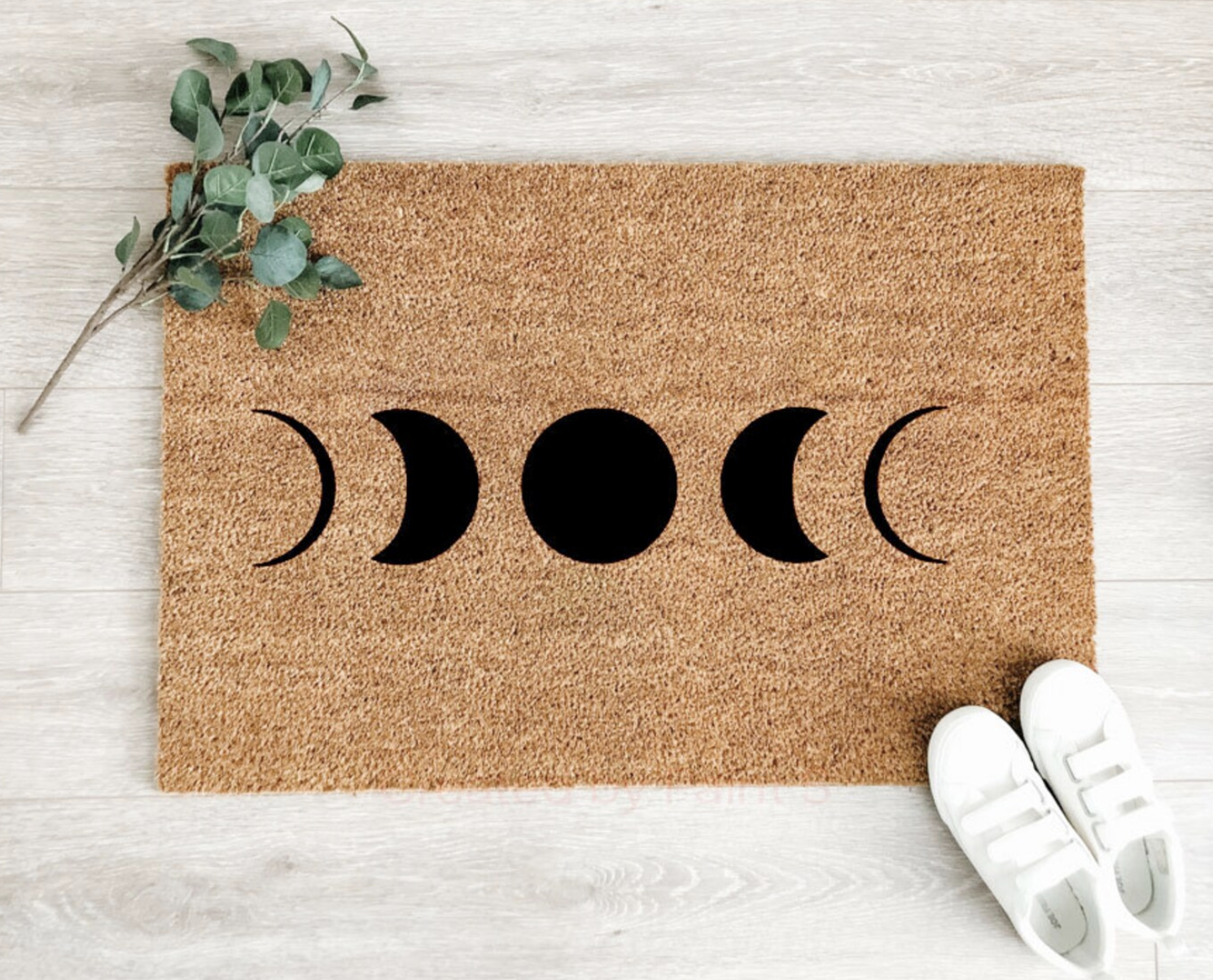 The doormat with the moon phases on the ground next to some shoes