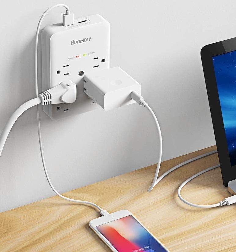 A phone and laptop plugged into the surge protector