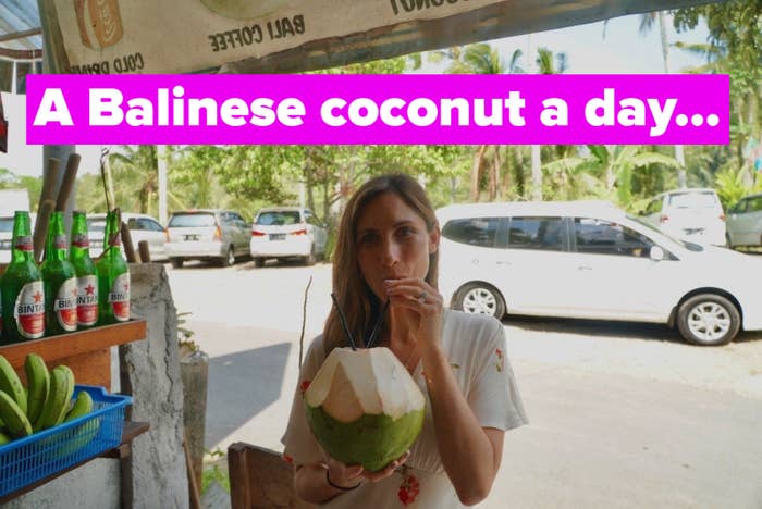 A woman drinking a coconut on the side of the road