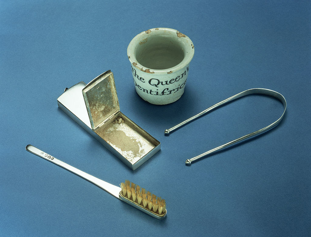 a small thimble, metal case, toothbrush and u-shaped scraper