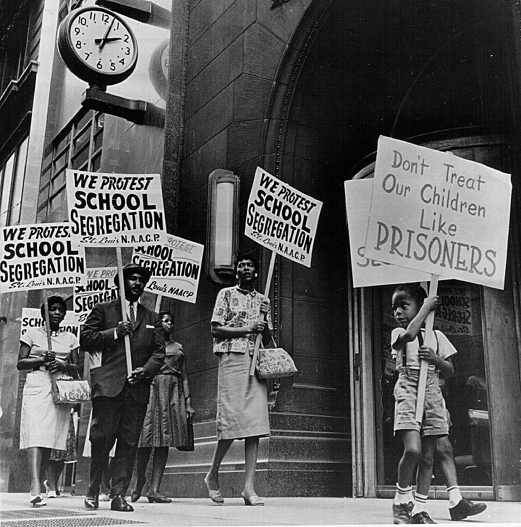 Black protesters outside with signs reading We protest school segregation