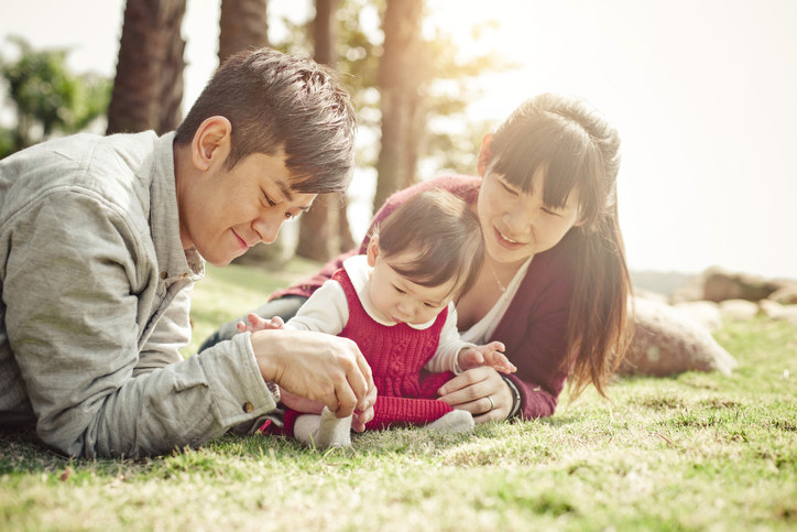 Chinese parents playing in the grass with their daughter