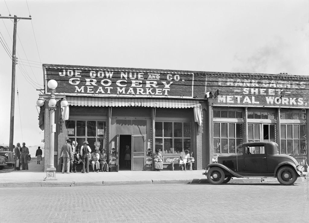 an old photo of a grocery storefront with people outside