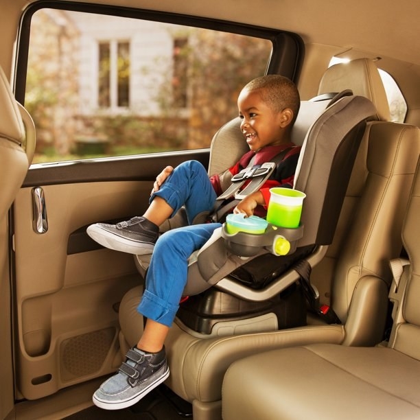 Boy sitting in car set with snack holder attached