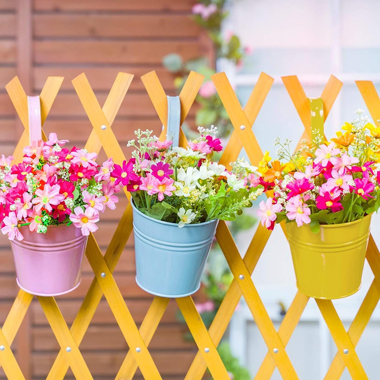 the flower pots with flowers in them hanging from a fence