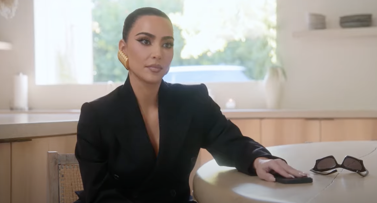 Kim sitting at a kitchen table with her hand resting on it