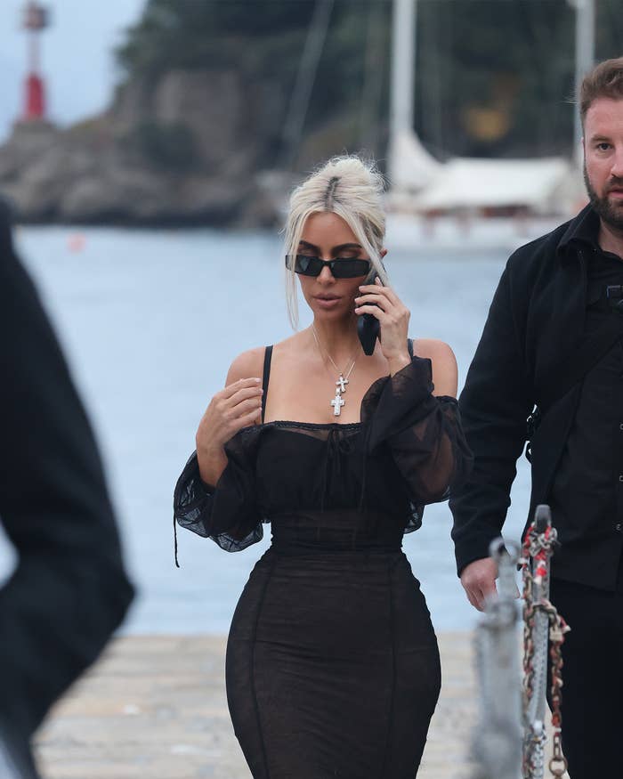 Kim in a formfitting strapless dress and on her cellphone