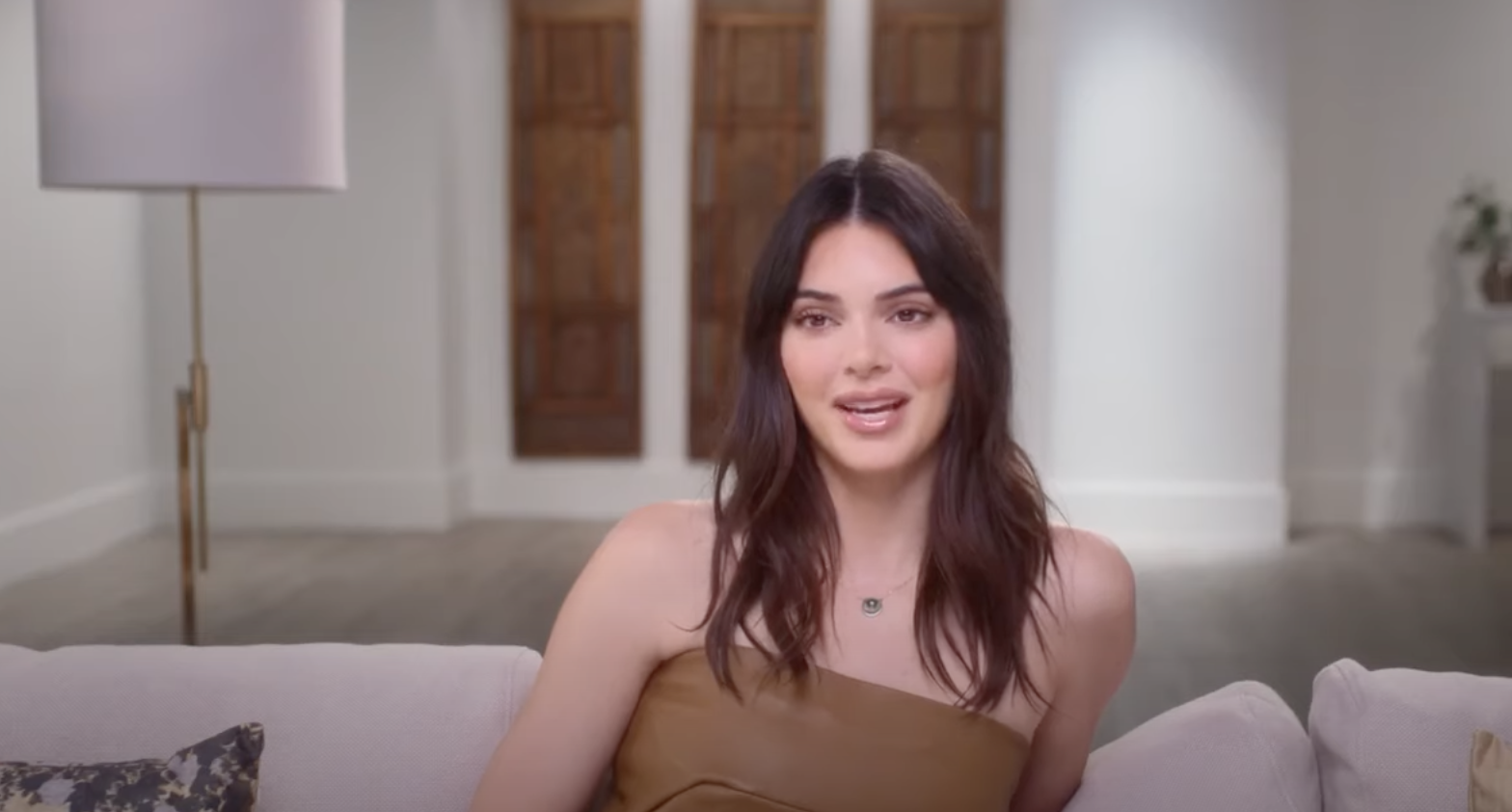 Kendall sitting on a couch and wearing a strapless top