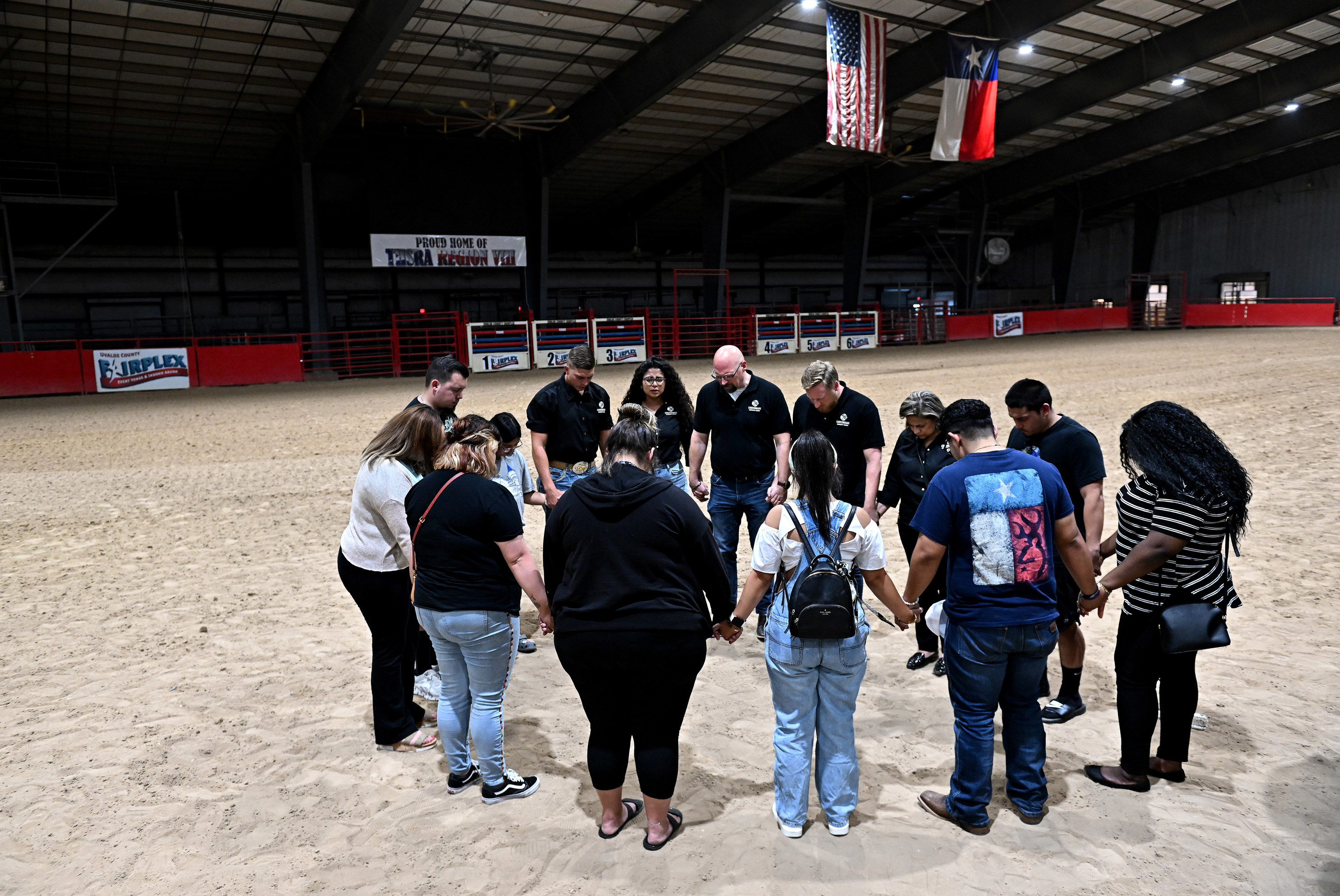 People hold hands and stand in a circle in a rodeo arena