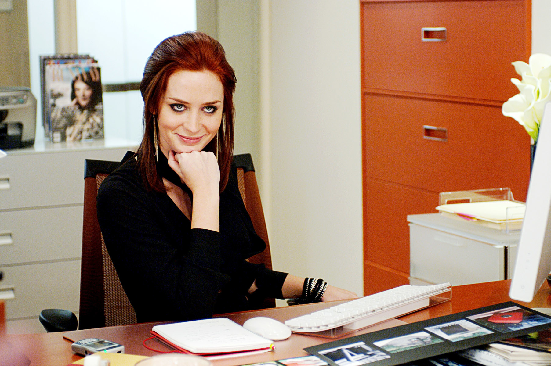 Emily smiling with her chin in her hand at a desk