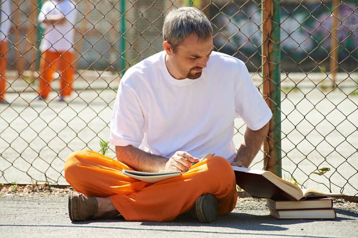 A prisoner taking notes from a textbook