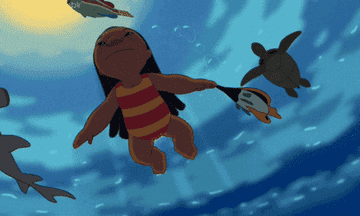 a gif a girl swimming with various sea creatures