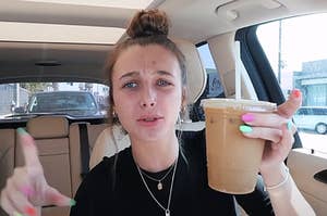 Emma Chamberlain sitting her a car and holding a cup of iced coffee