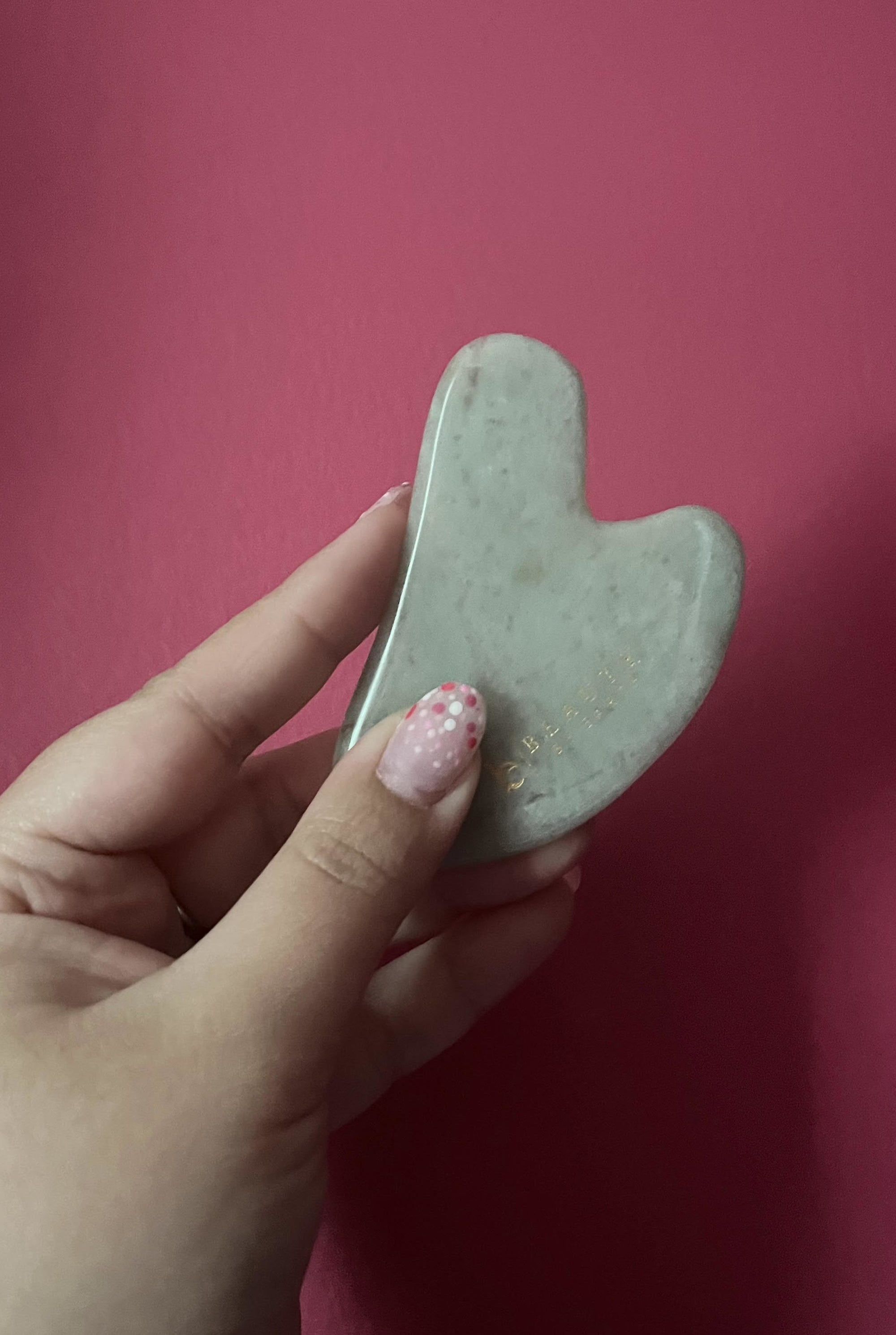 Bianca holding up the gua sha against a plain wall