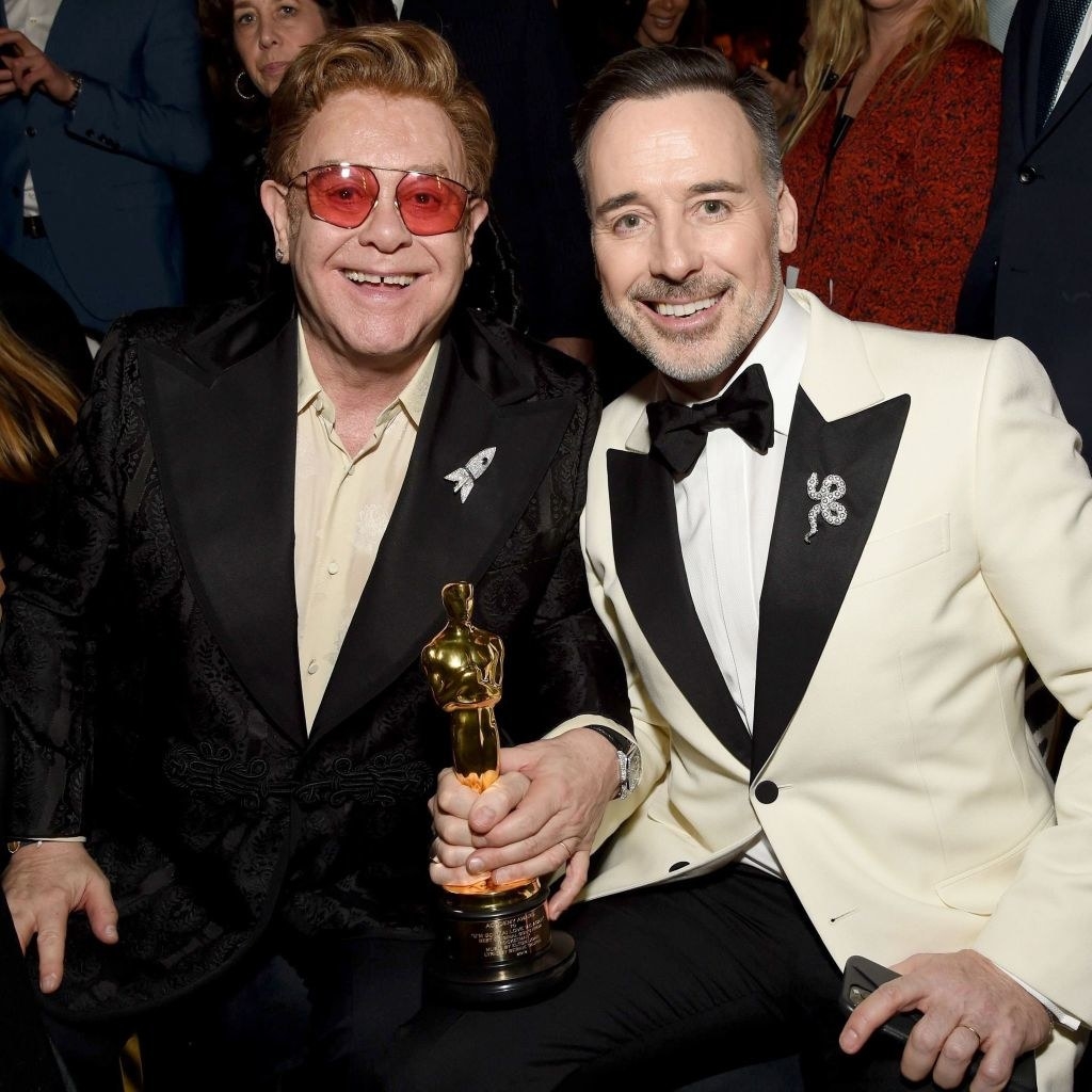 Elton John and David Furnish attend the 28th Annual Elton John AIDS Foundation Academy Awards Viewing Party, holding an Oscar