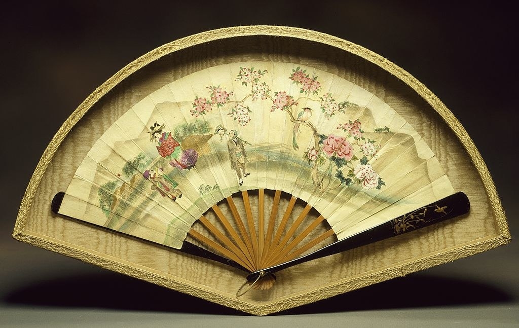 a fan with a scene of people in the countryside with cherry blossoms