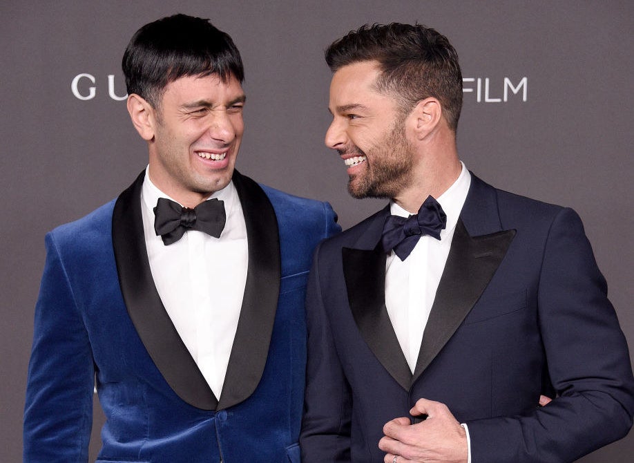 Ricky and Jwan smiling at each other on a red carpet