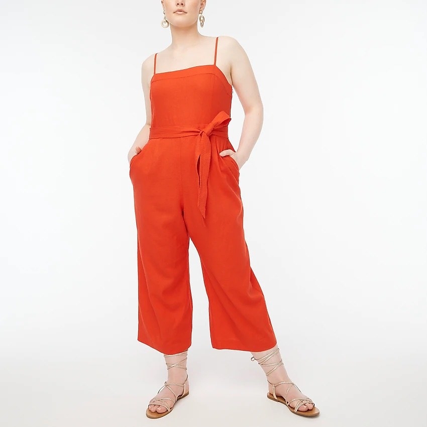 model wearing the red-orange jumpsuit with gladiator sandals