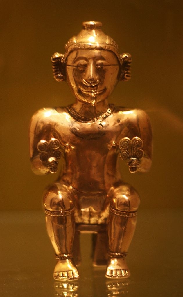a small gold container in the shape of a person sitting down
