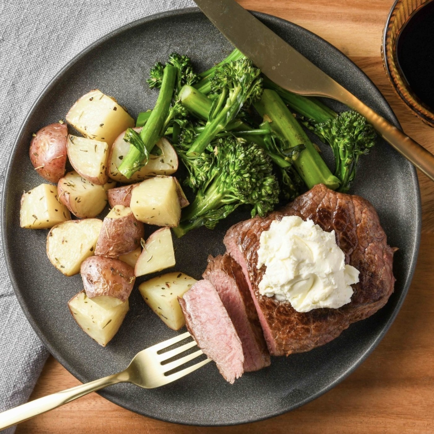 A dinner plate with medium steak, rosemary potatoes and tender steamed broccoli