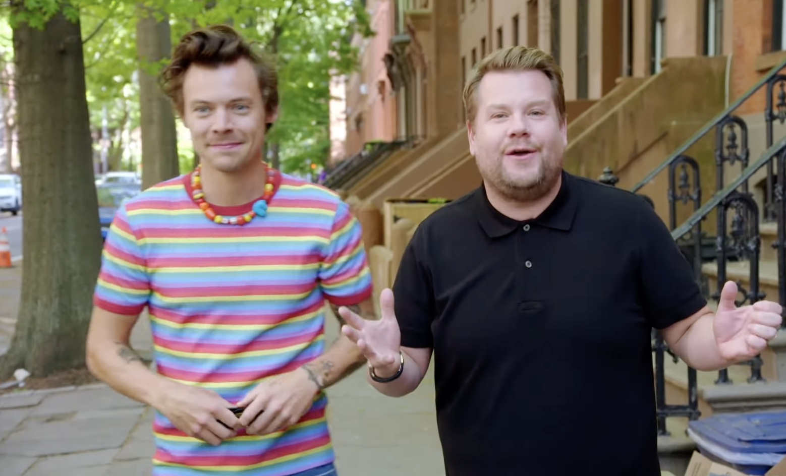Corden and Styles on the sidewalk facing the camera