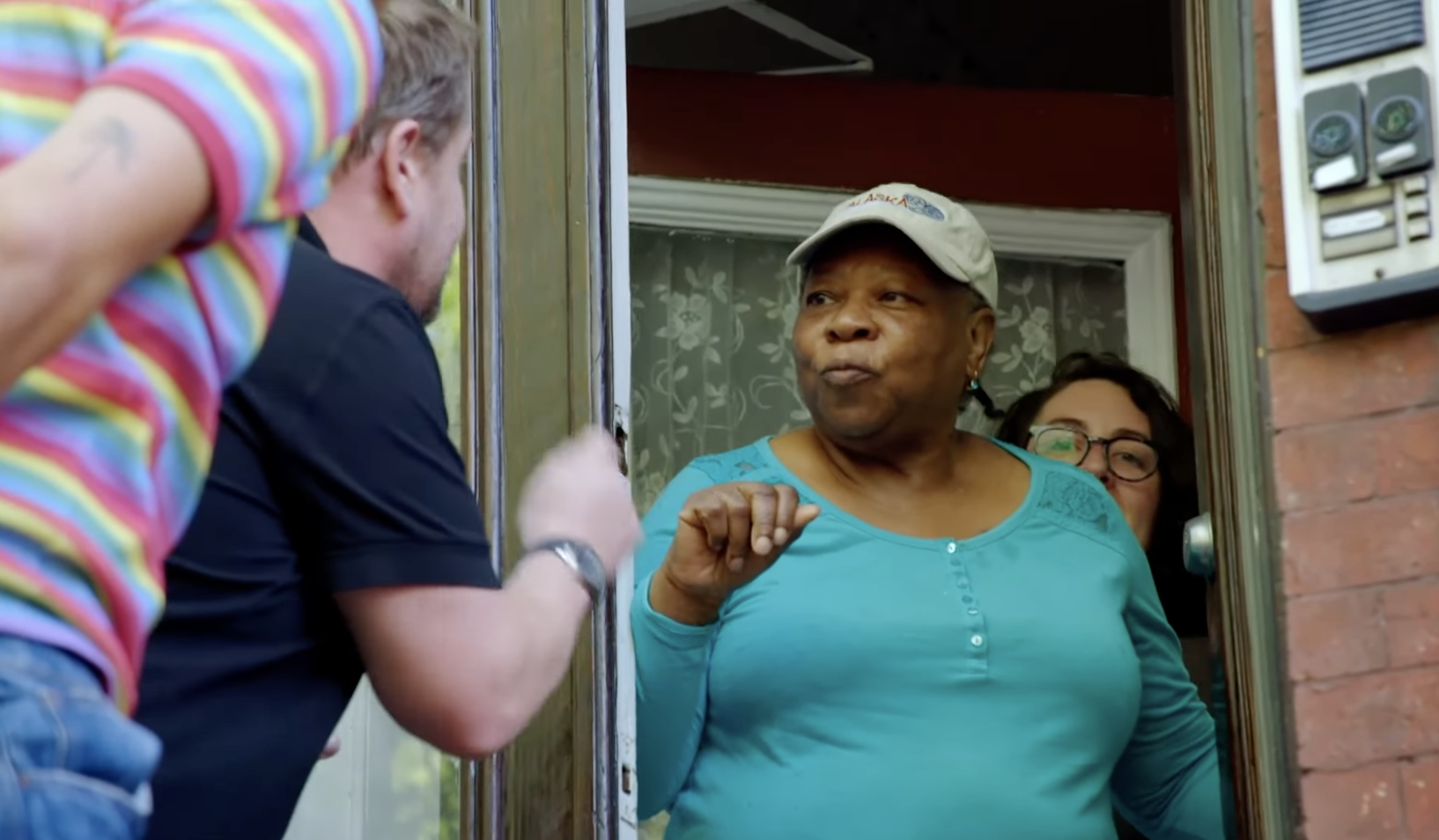 Corden and Styles lean forward at a stranger&#x27;s door, where an older woman looks on quizzically