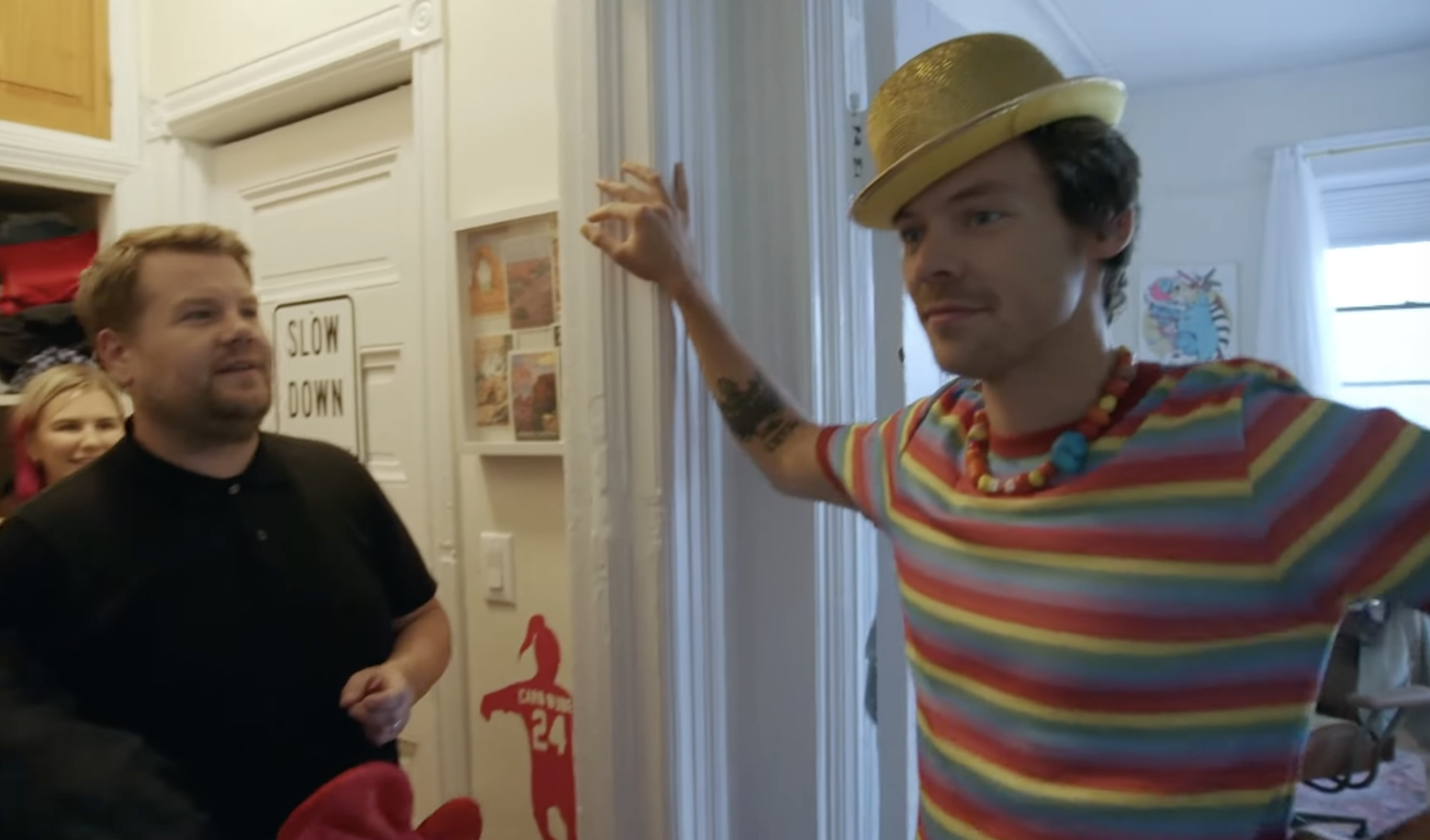 Styles wears a bowler hat, standing in the apartment