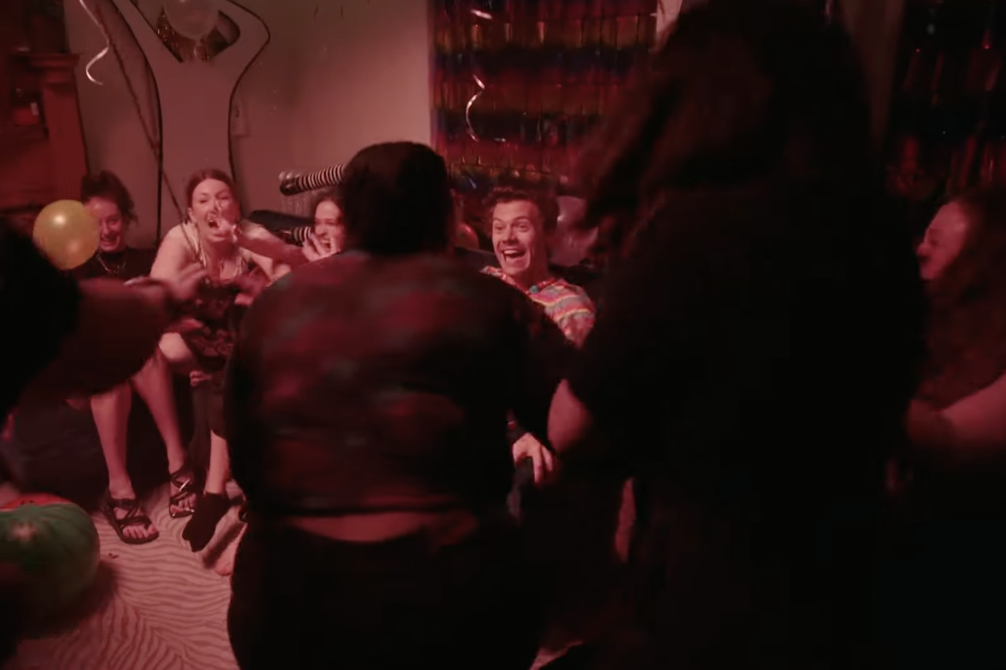 A group of people are blurred in excitement, jumping up and down and reacting to Harry Styles' presence