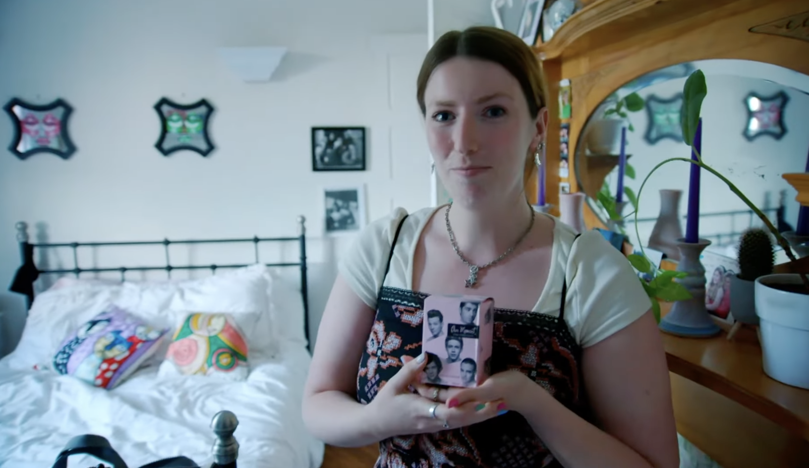 A woman faces the camera, holding up a box with Harry Styles&#x27; face collaged onto it