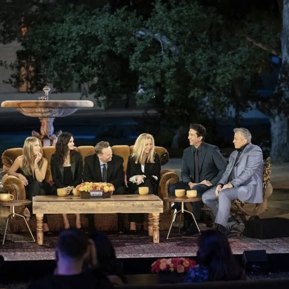 The cast of Friends sits on a stage together
