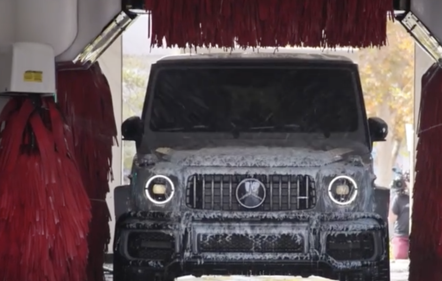 A luxe SUV is sprayed with soapy foam in a car wash