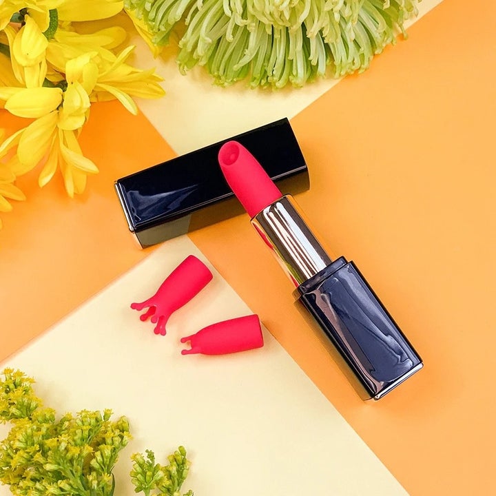 Lipstick vibrator next to two interchangeable heads