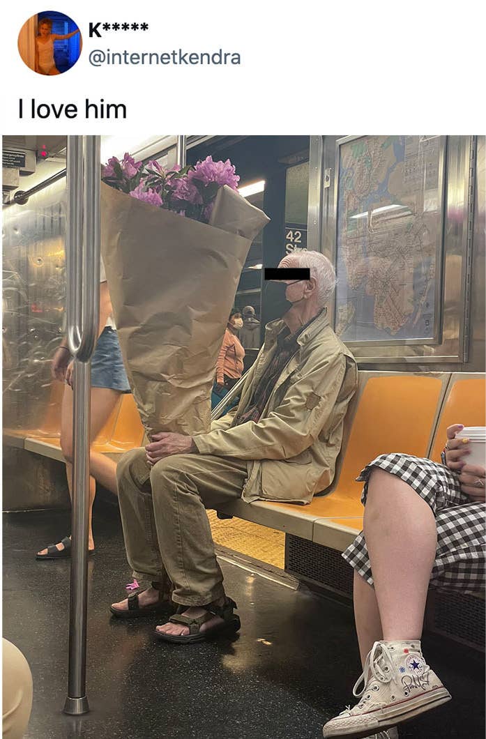 A man on a subway holding a bouquet of flowers