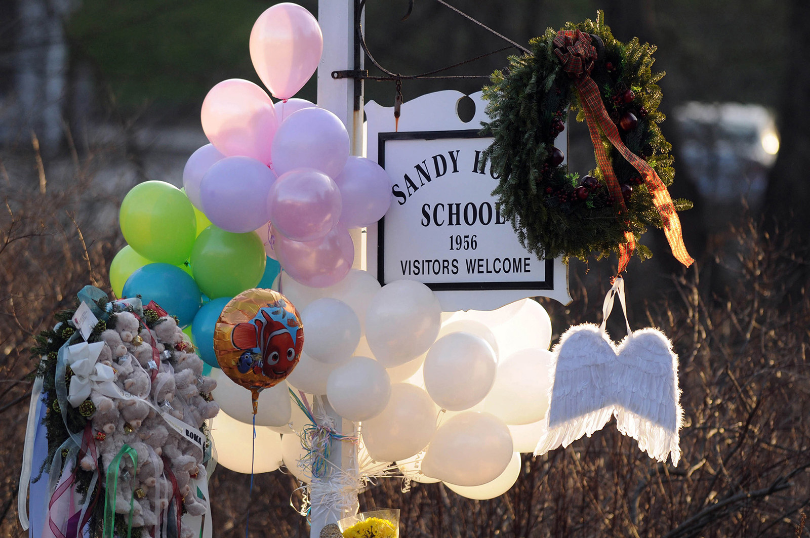 A memorial with flowers and balloons hanging on the Sandy Hook School sign