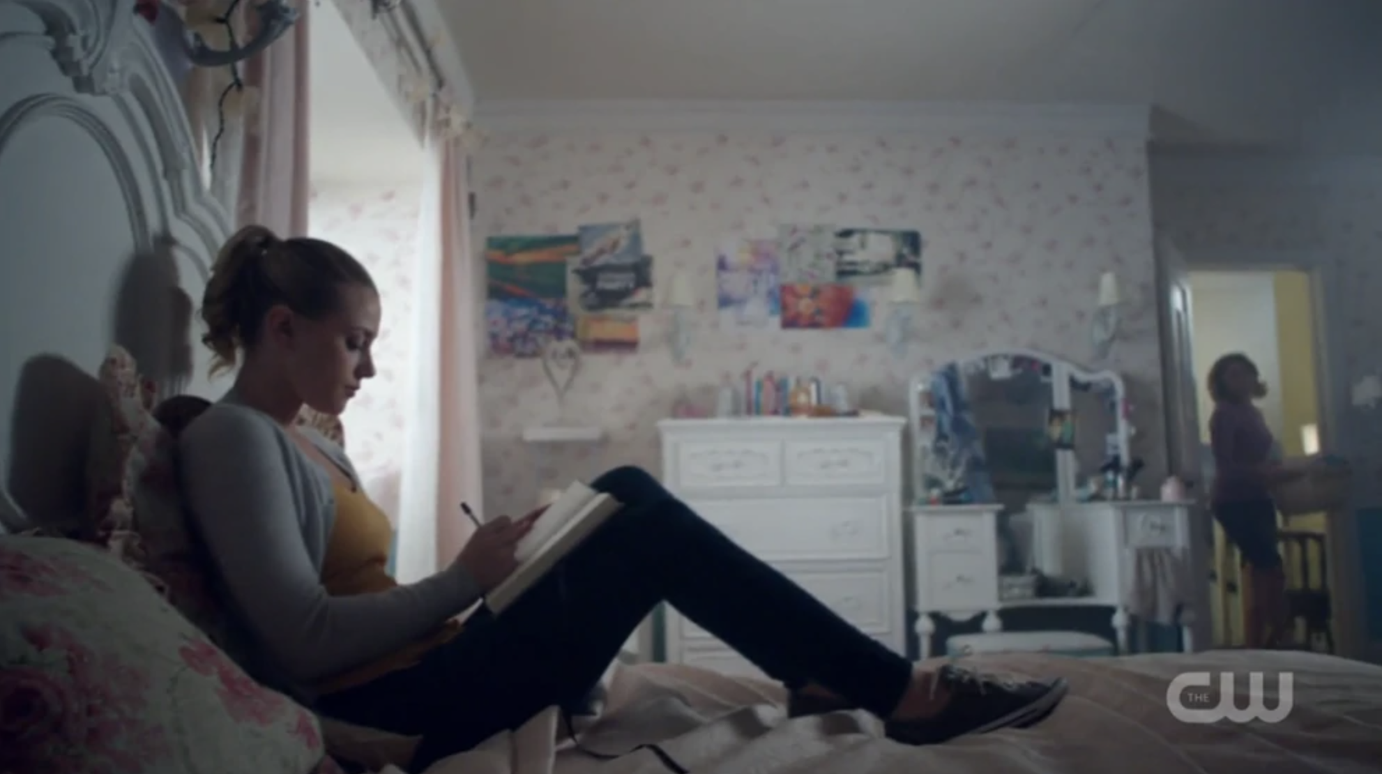 A character lying in bed and writing in her journal while wearing shoes