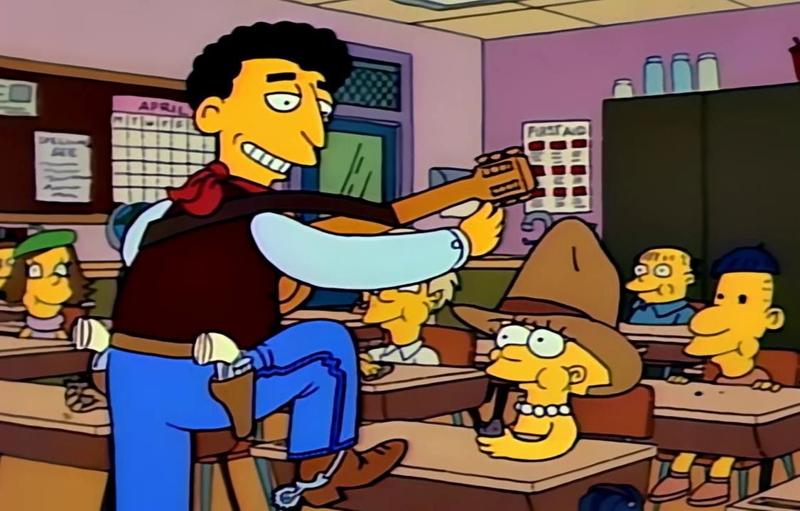 In a school classroom, a man in a cowboy outfit has his foot up on a desk, playing the guitar, Lisa is in front of him with a large hat on