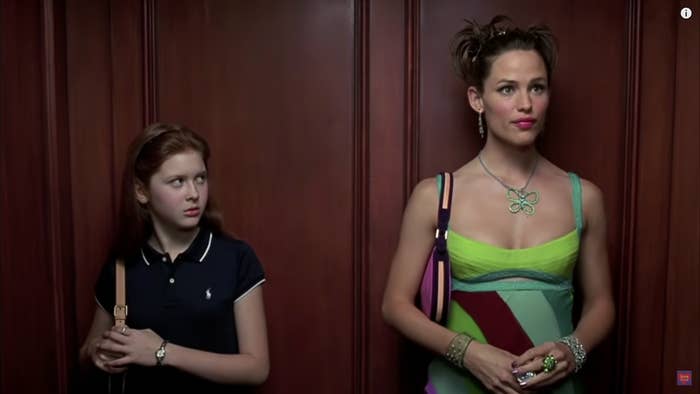 A tween girl looks at a glamorously dressed woman in an elevator.