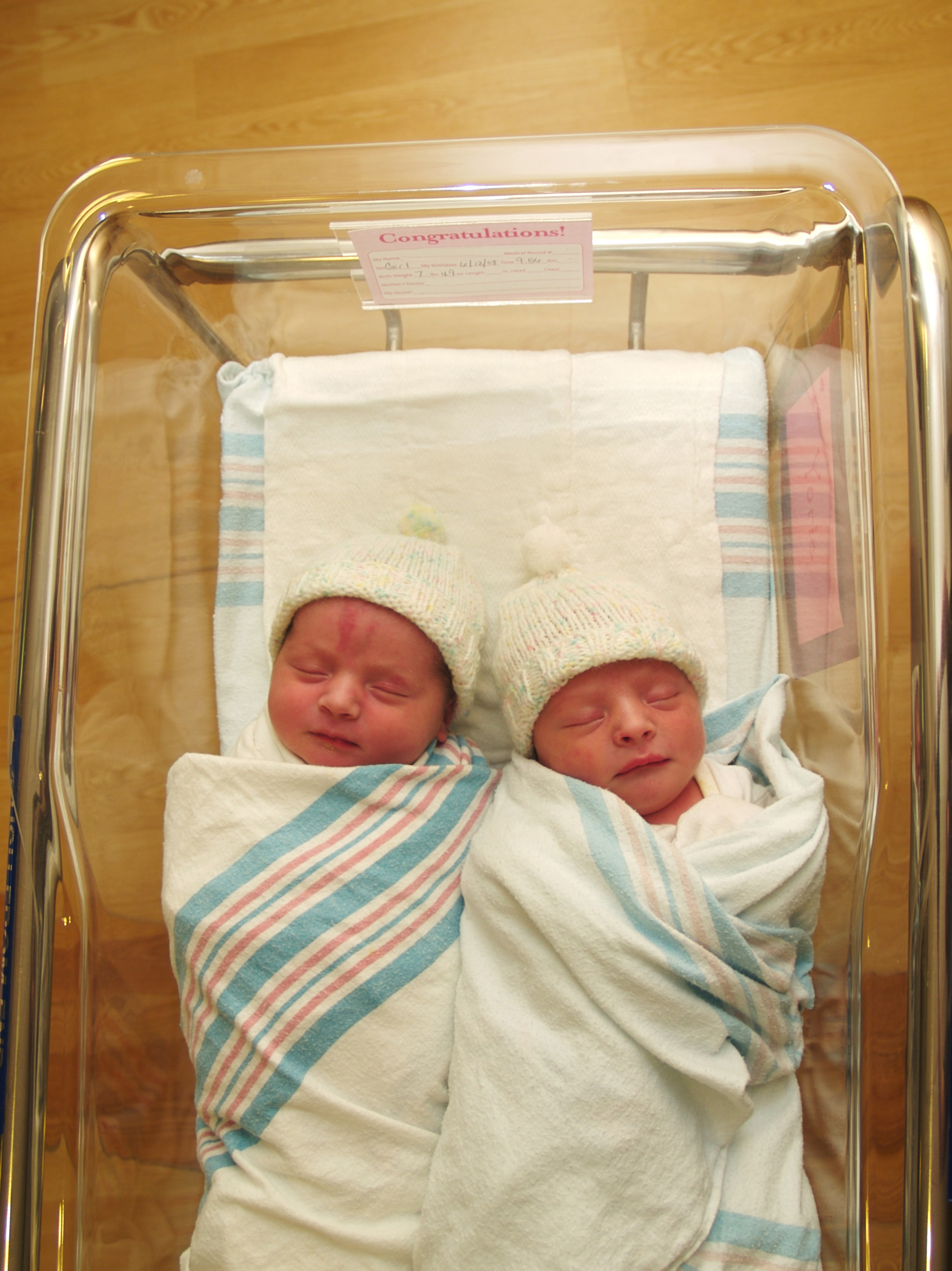 Twins sit in a crib in the hospital
