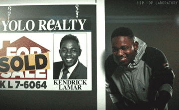 Kendrick Lamar standing in front of a sold realty sign