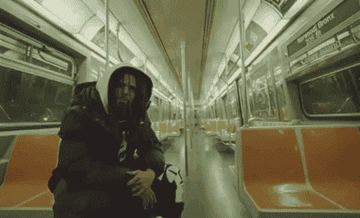 A gif of J. Cole sitting on a subway train