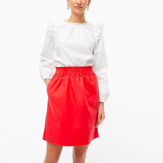 Model wearing red skirt and white top
