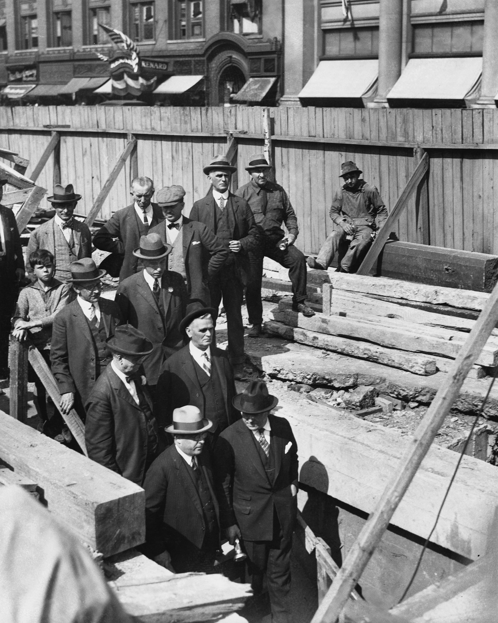 Men wearing coats and hats walk down a staircase underground